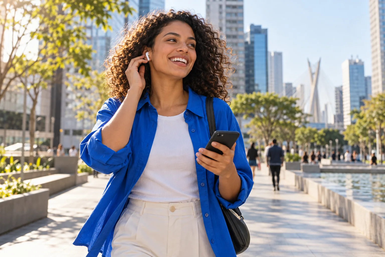 Pessoa caminha por uma praça urbana usando o celular com fone de ouvido